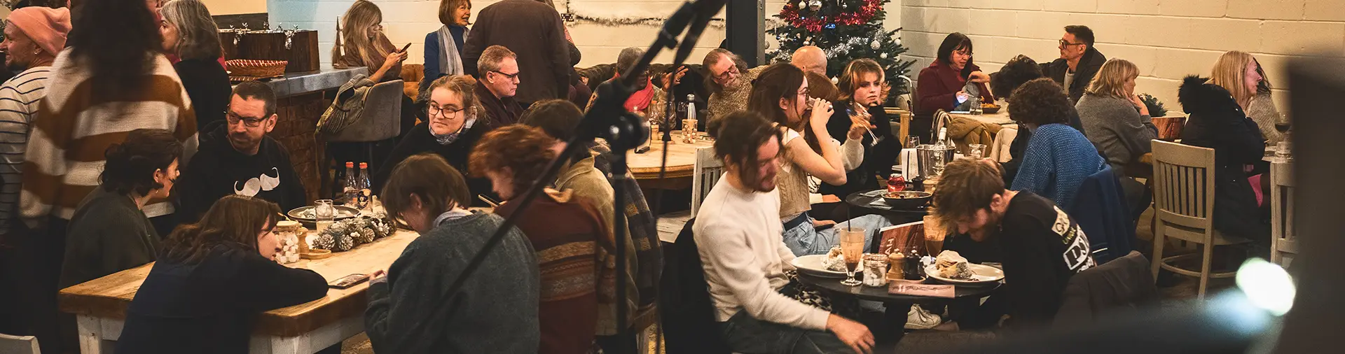 Large crowd sitting at tables at an open mic event.